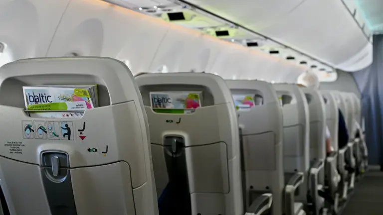 Skats uz airBaltic lidmašīnas pasažieru salona krēsliem ar zīmola žurnāliem atzveltnēs.