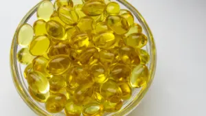 Dzeltenas D vitamīna kapsulas stikla traukā, kas simbolizē uztura bagātinātājus tumšajā sezonā.
