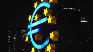 Izgaismota eiro zīme naktī, kas simbolizē Eiropas Centrālās bankas finanšu politiku.
