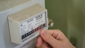 Cilvēka roka nolasa rādījumus no gāzes vai elektrības skaitītāja mājoklī