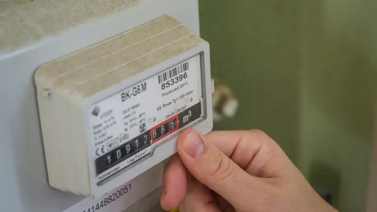 Cilvēka roka nolasa rādījumus no gāzes vai elektrības skaitītāja mājoklī