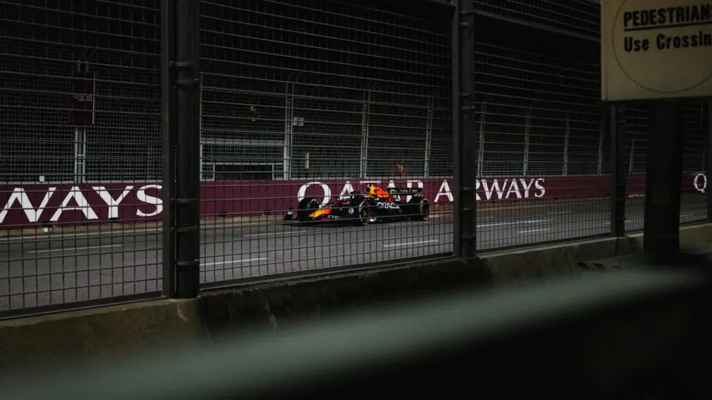 Formula 1 sacīkšu auto ātrumā veic pagriezienu F1 trases norobežotajā posmā.