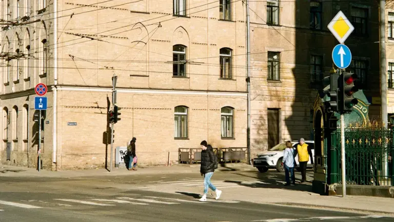 Cilvēki šķērso ielu Rīgā, gatavojoties jaunajam mācību gadam un 1. septembrim.