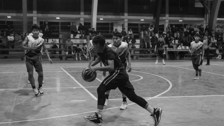 Basketbola spēlētājs driblē bumbu sporta zāles laukumā spēles laikā