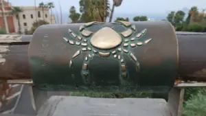 Bronzas vēža zīmes simbols uz cilindriska monumenta vasaras dienā ar jūras ainavu