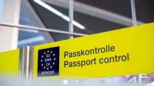 Dzeltena norāde ar uzrakstu pasu kontrole lidostas terminālī pirms ceļojuma.