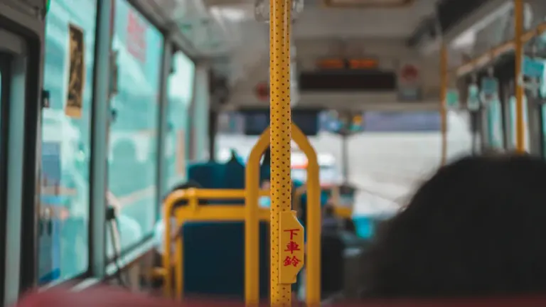 Dzeltens rokturis sabiedriskā transporta autobusā ar skatu uz tukšiem sēdekļiem un logiem.